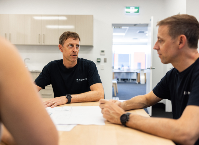 Deimos Team gather around table to discuss new advancements in technology